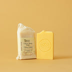 Two bars of soap, one wrapped and one unwrapped, on a beige background